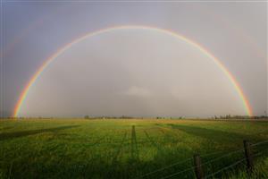 Double rainbow spread wide across farmland.