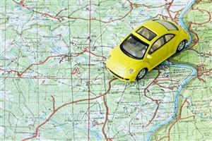 Yellow toy car placed on a road map